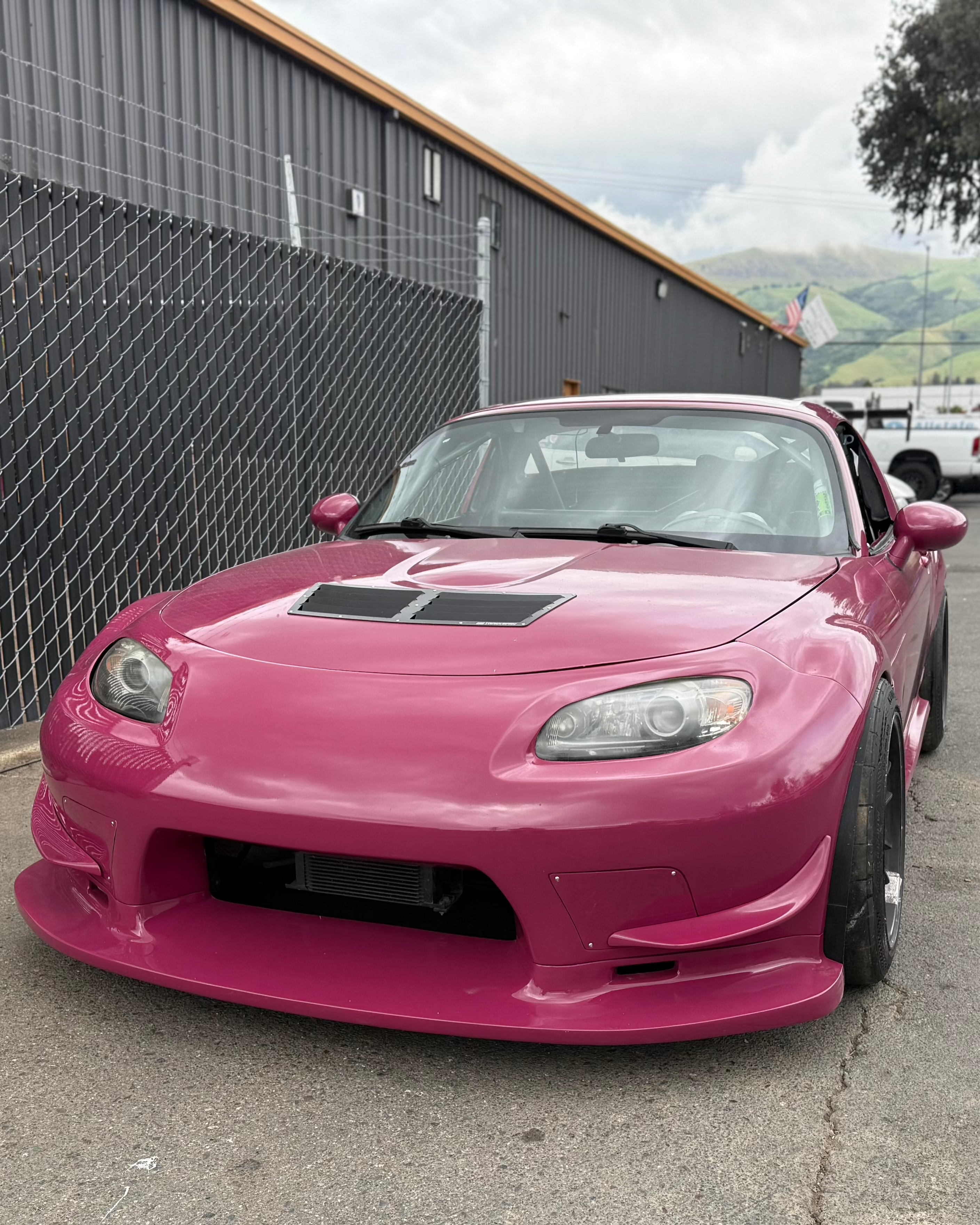 Front three-quarter view of a pink Mazda MX-5 Miata NC with the Epsilon+ front bumper
