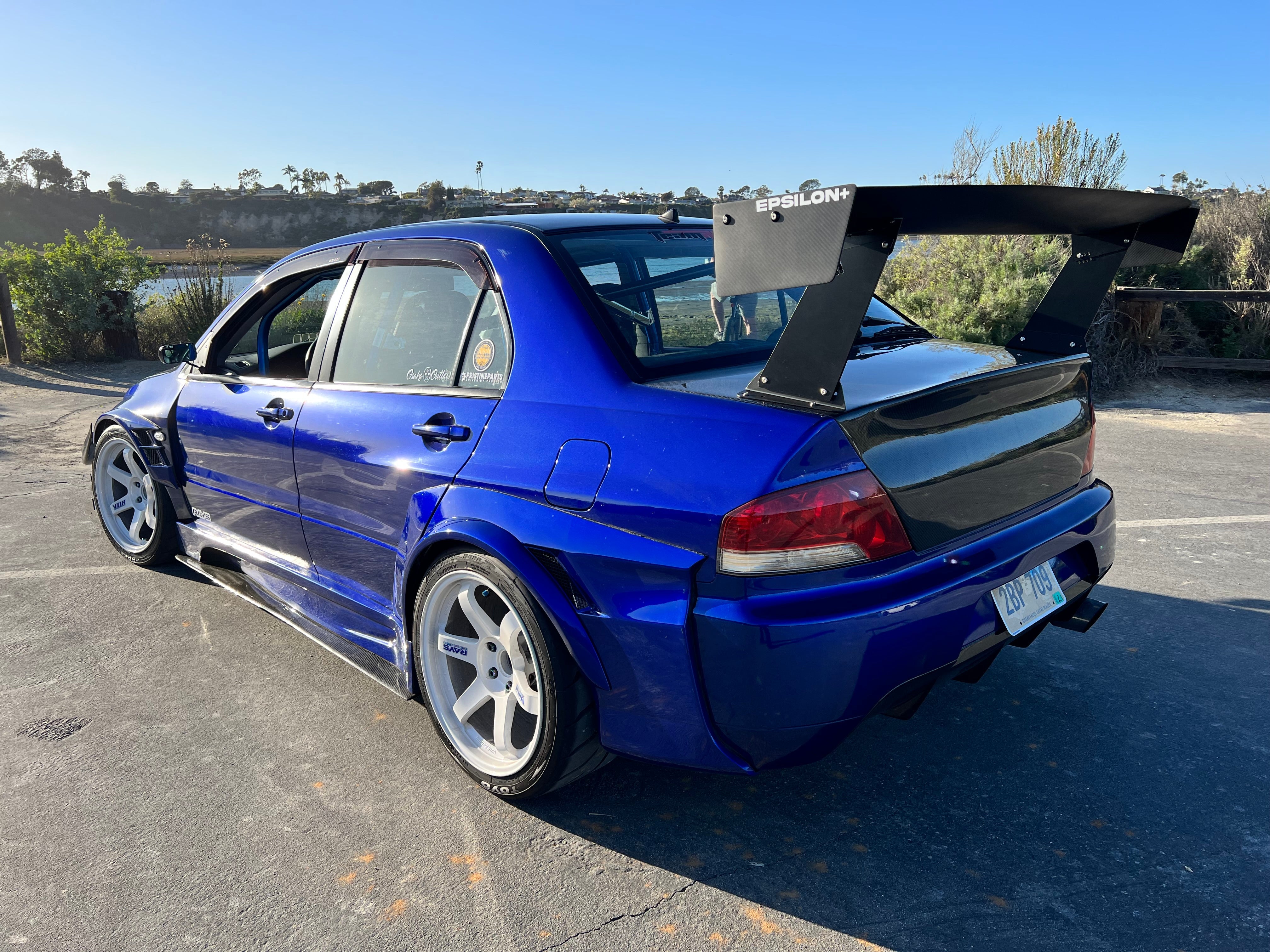 Rear three-quarter view of a blue Mitsubishi Evo with GT wing parked outdoors