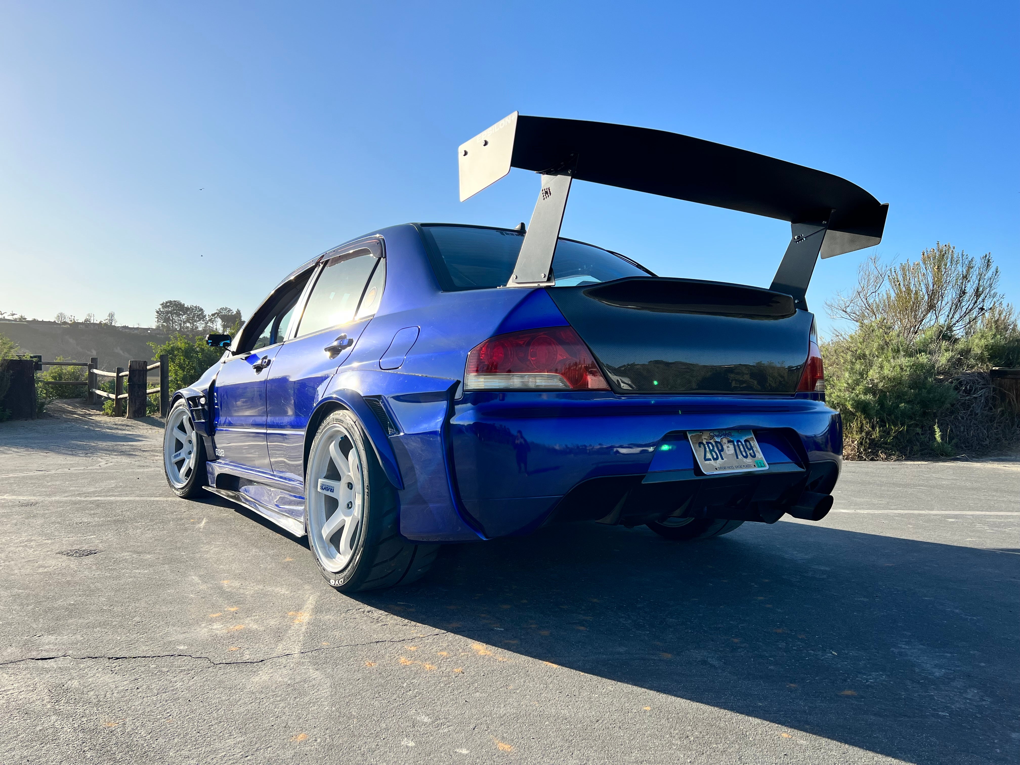 Rear view of a blue Mitsubishi Evo showing the GT wing and taillights