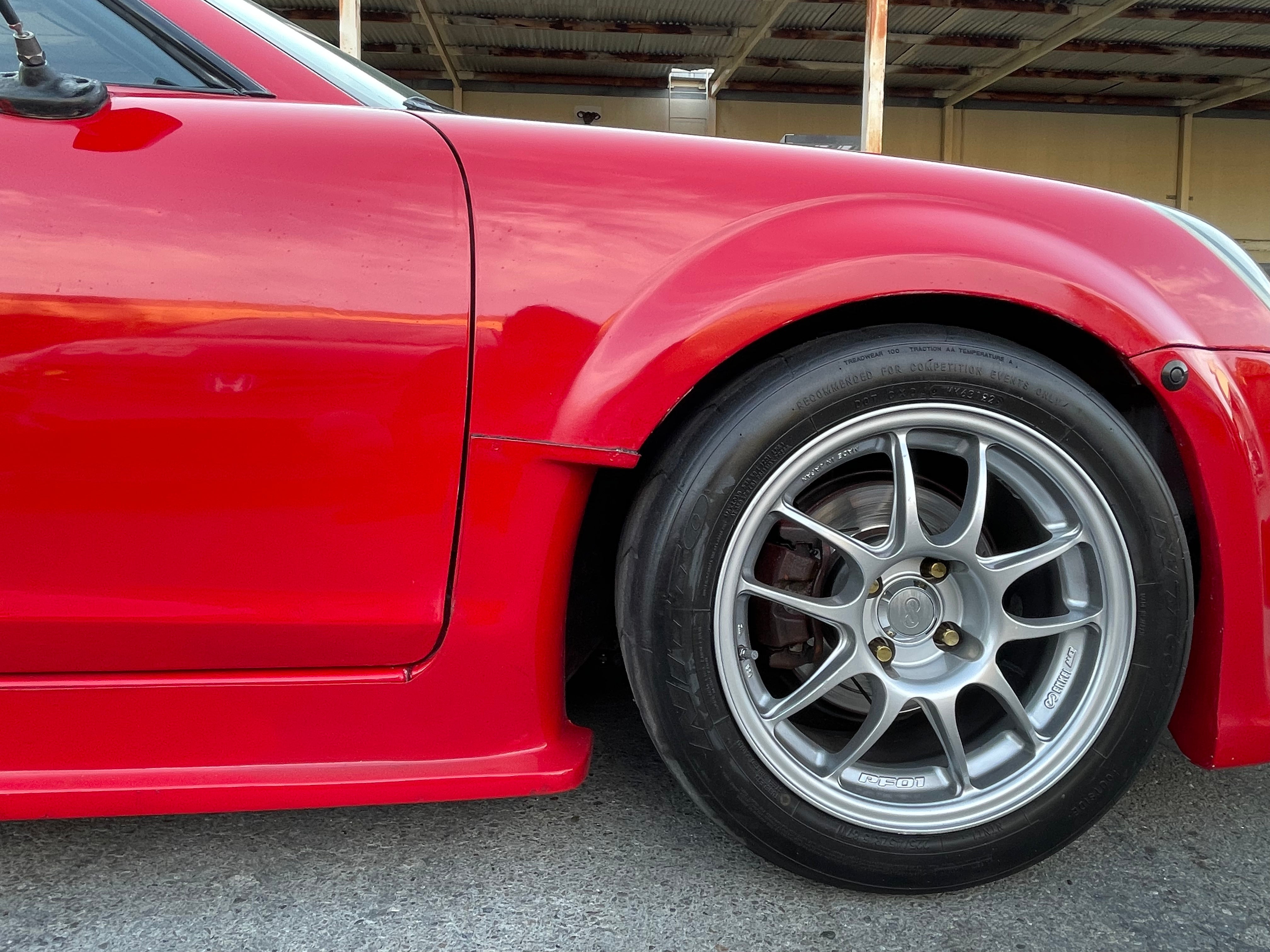 Close-up of the widened fender arch and wheel clearance on a red MR2 Spyder