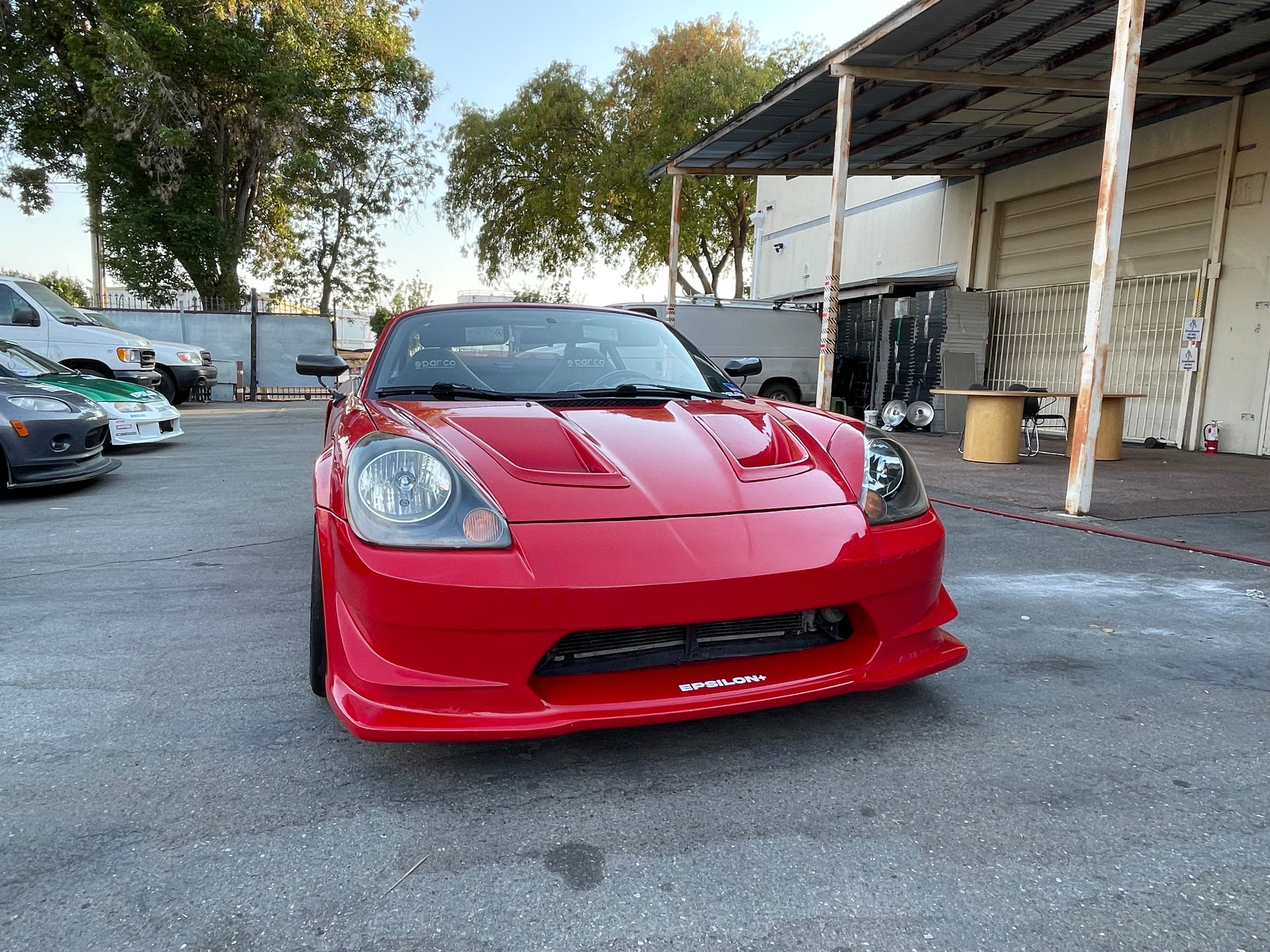 Front three-quarter view of a red MR2 Spyder with front bumper parked outdoors