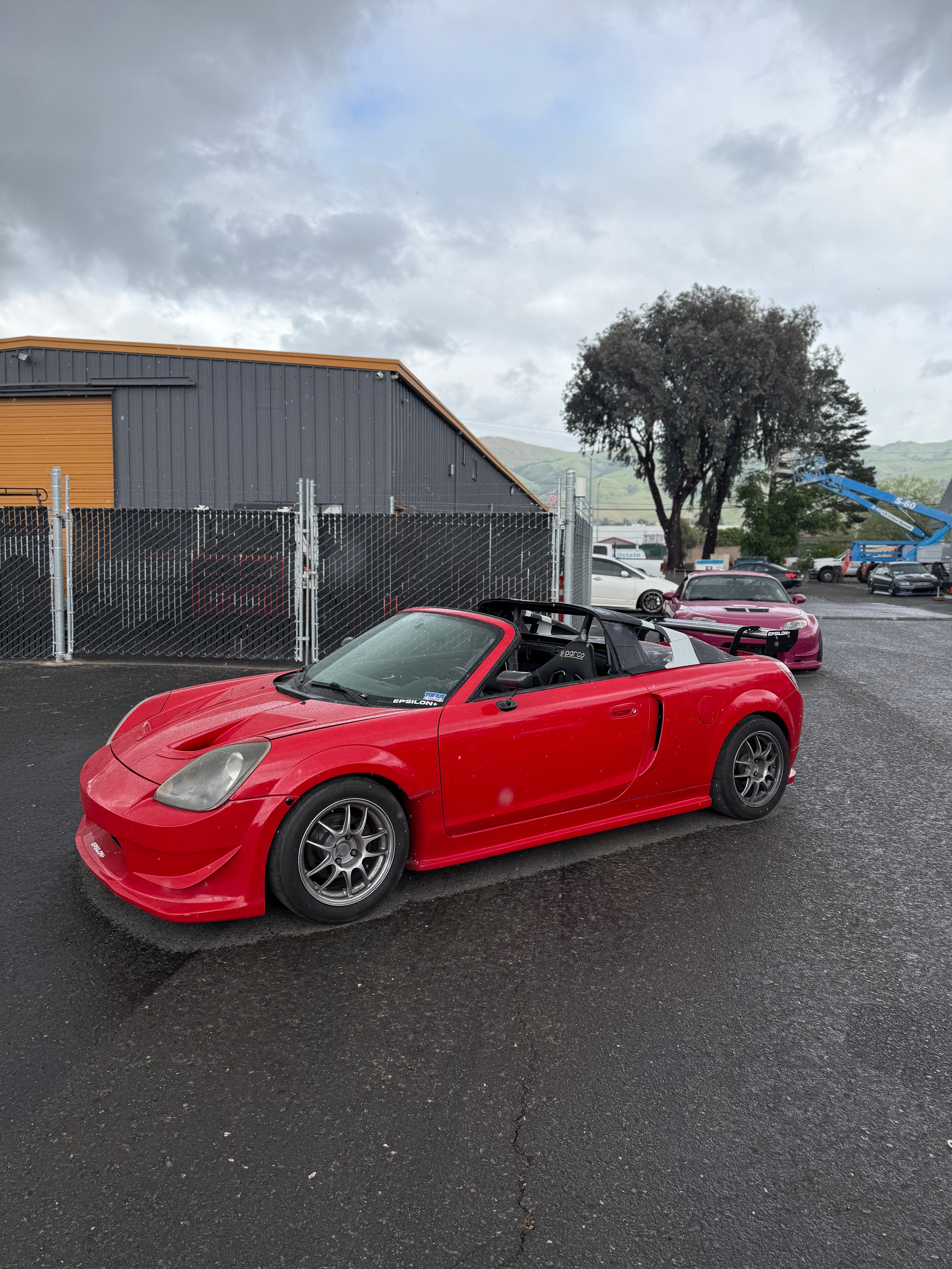 Front three-quarter view of a red MR2 Spyder with front bumper and hood vents