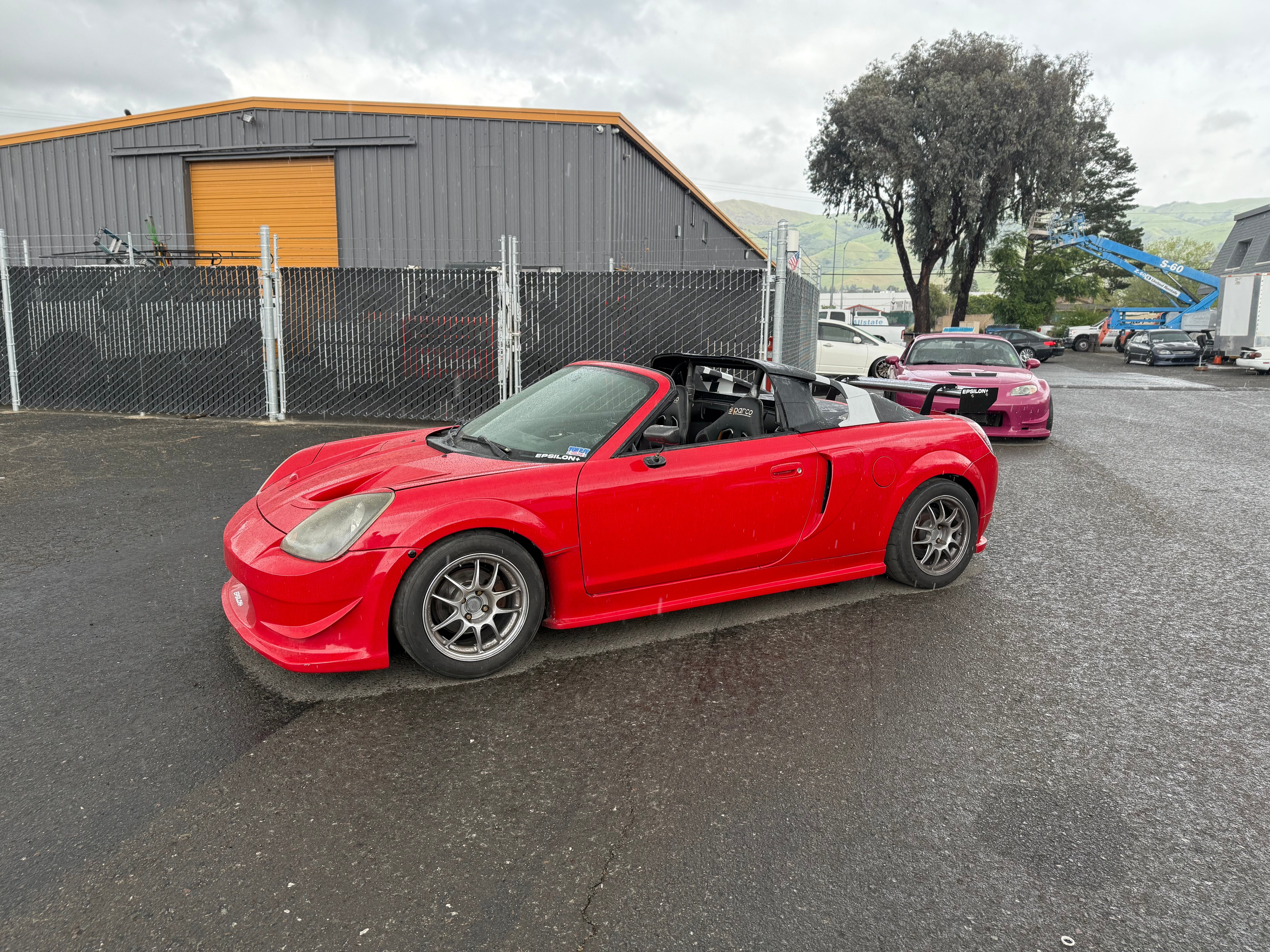 Side-rear view of a red Toyota MR2 Spyder with aero kit fitted