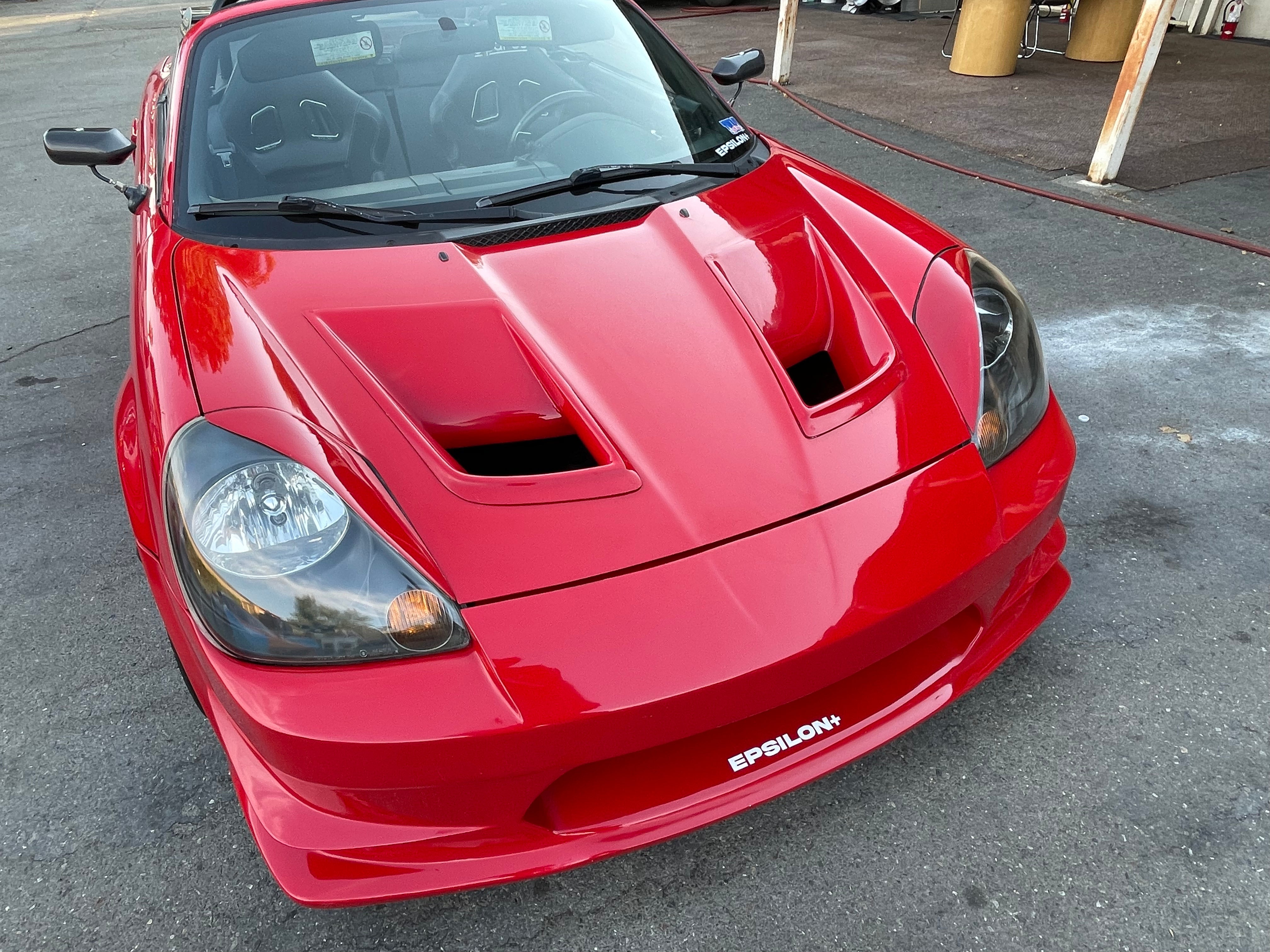 Front three-quarter view of a red Toyota MR2 Spyder with headlight eyelids fitted
