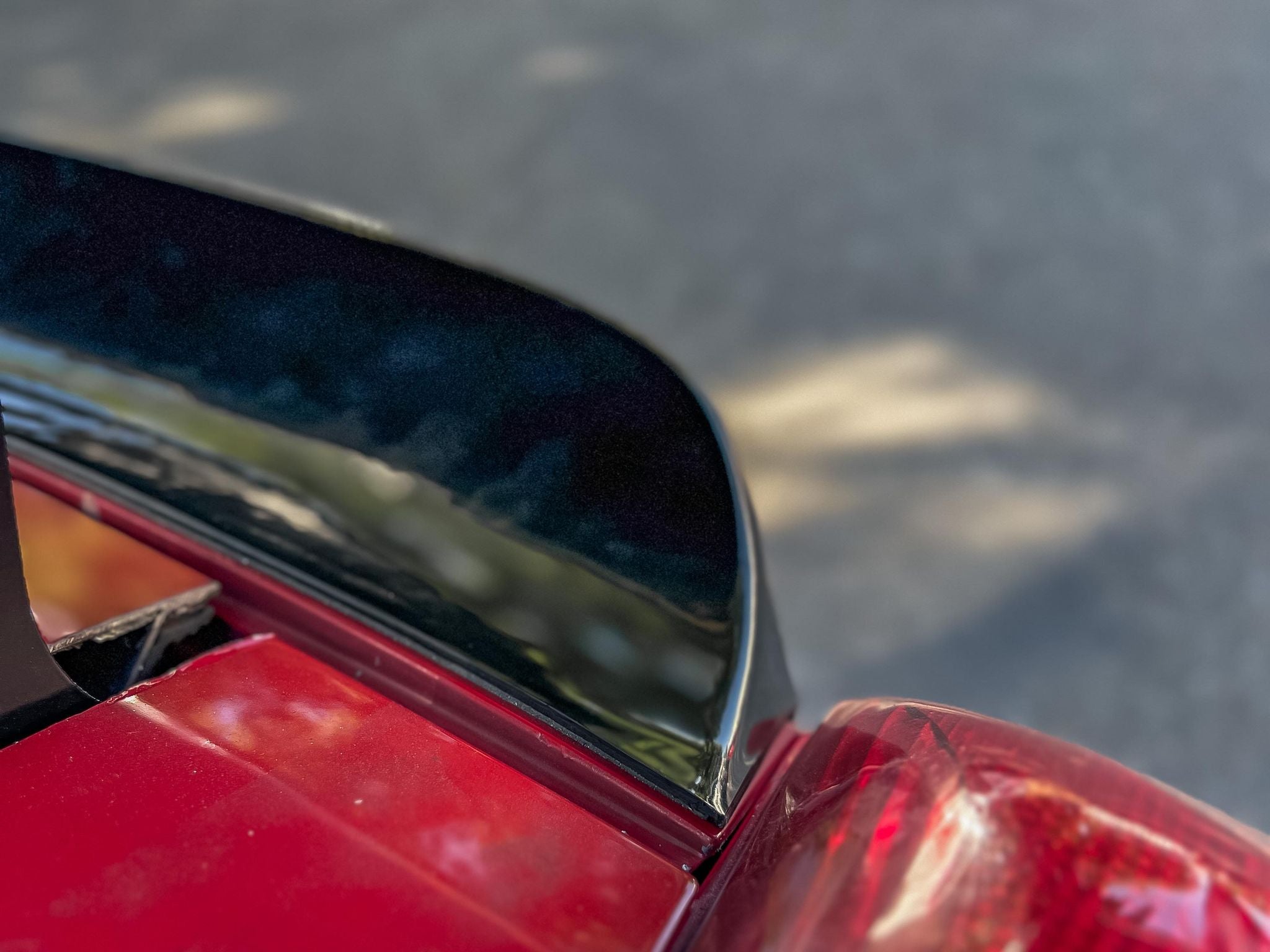 Detail of the duckbill spoiler corner and rear glass on a red MR2 Spyder