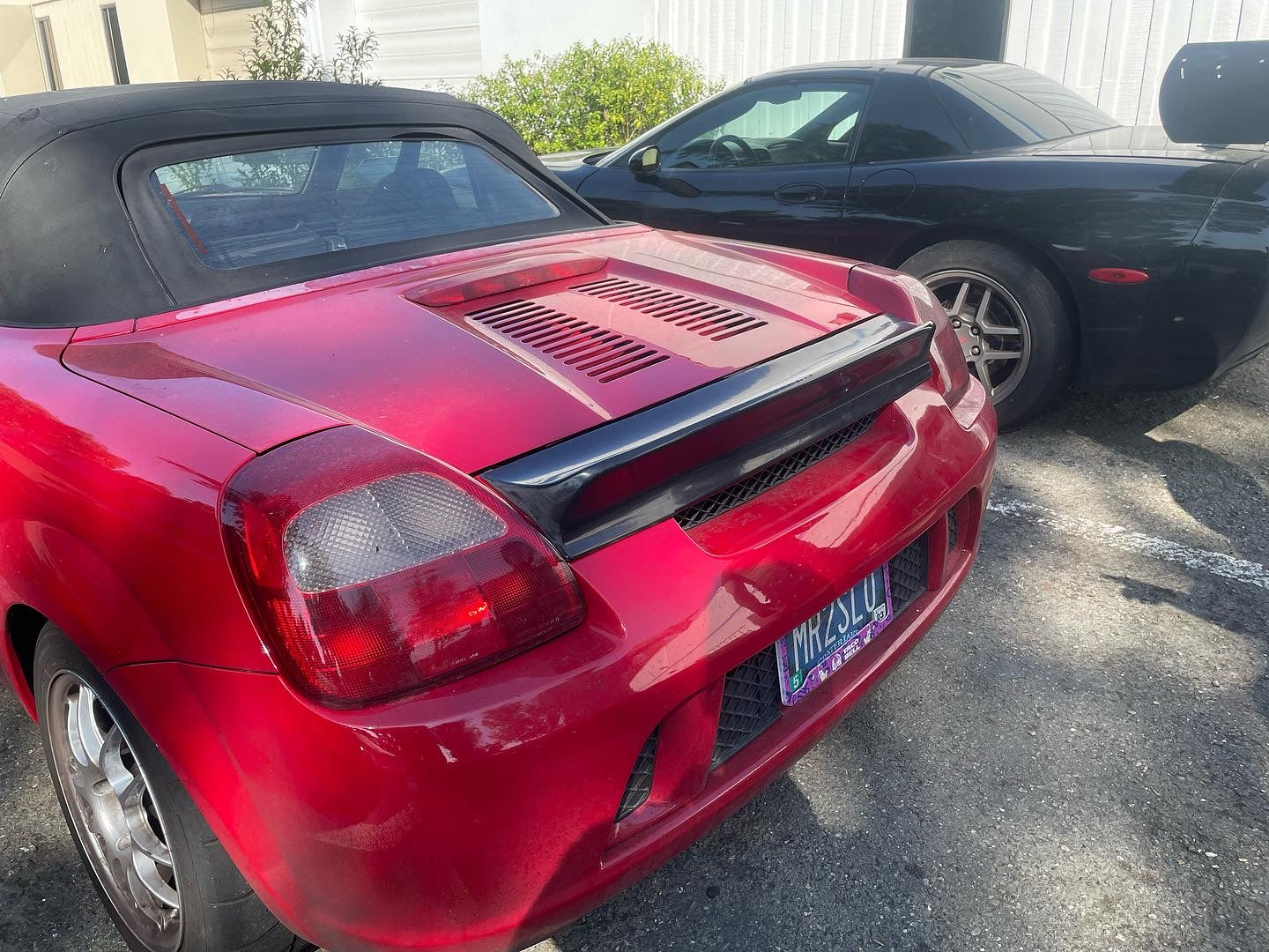 Rear three-quarter view of a red MR2 Spyder with duckbill spoiler in a parking lot