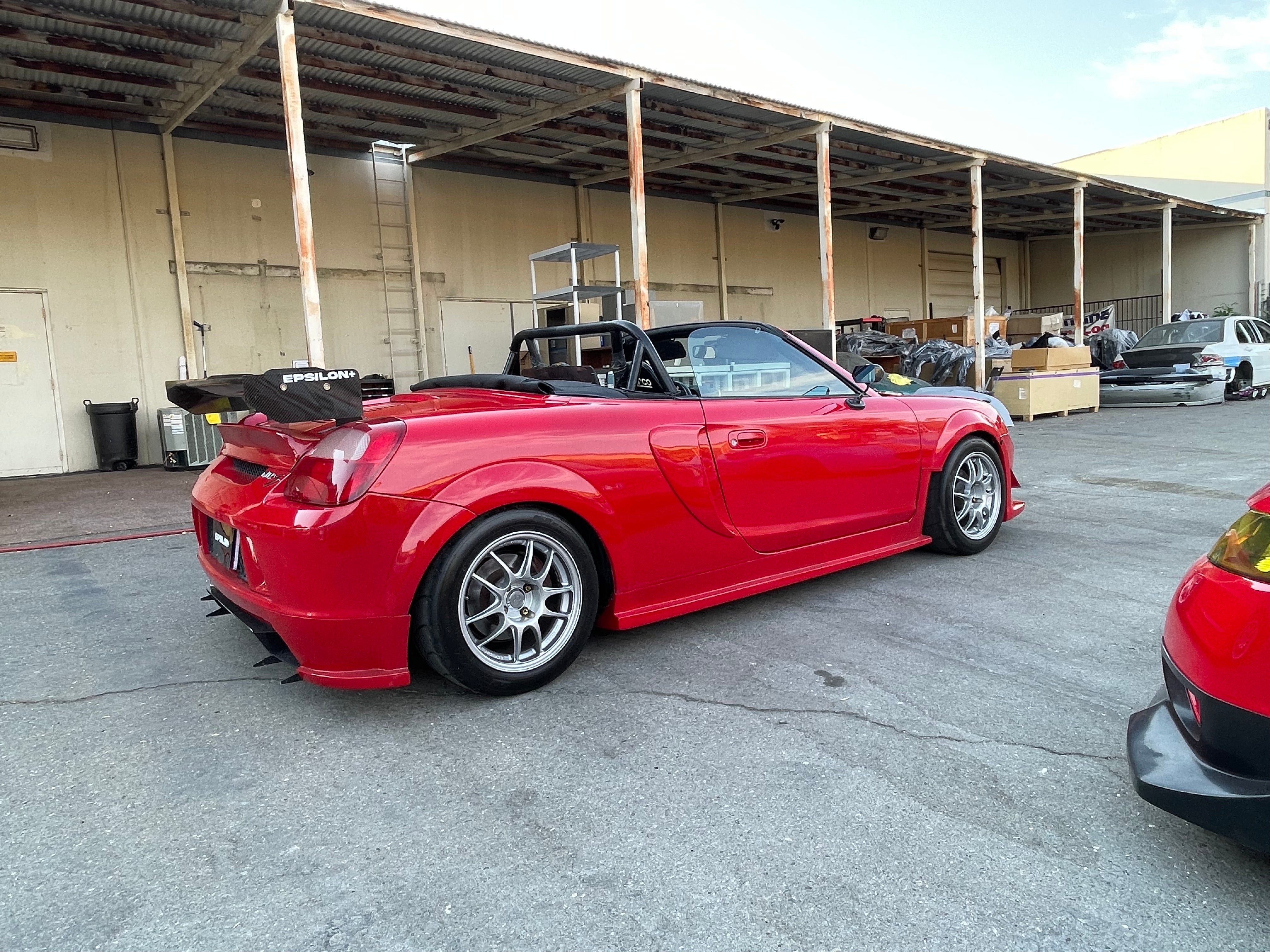 Side-rear view of a red MR2 Spyder showing the side skirt and fender combo profile