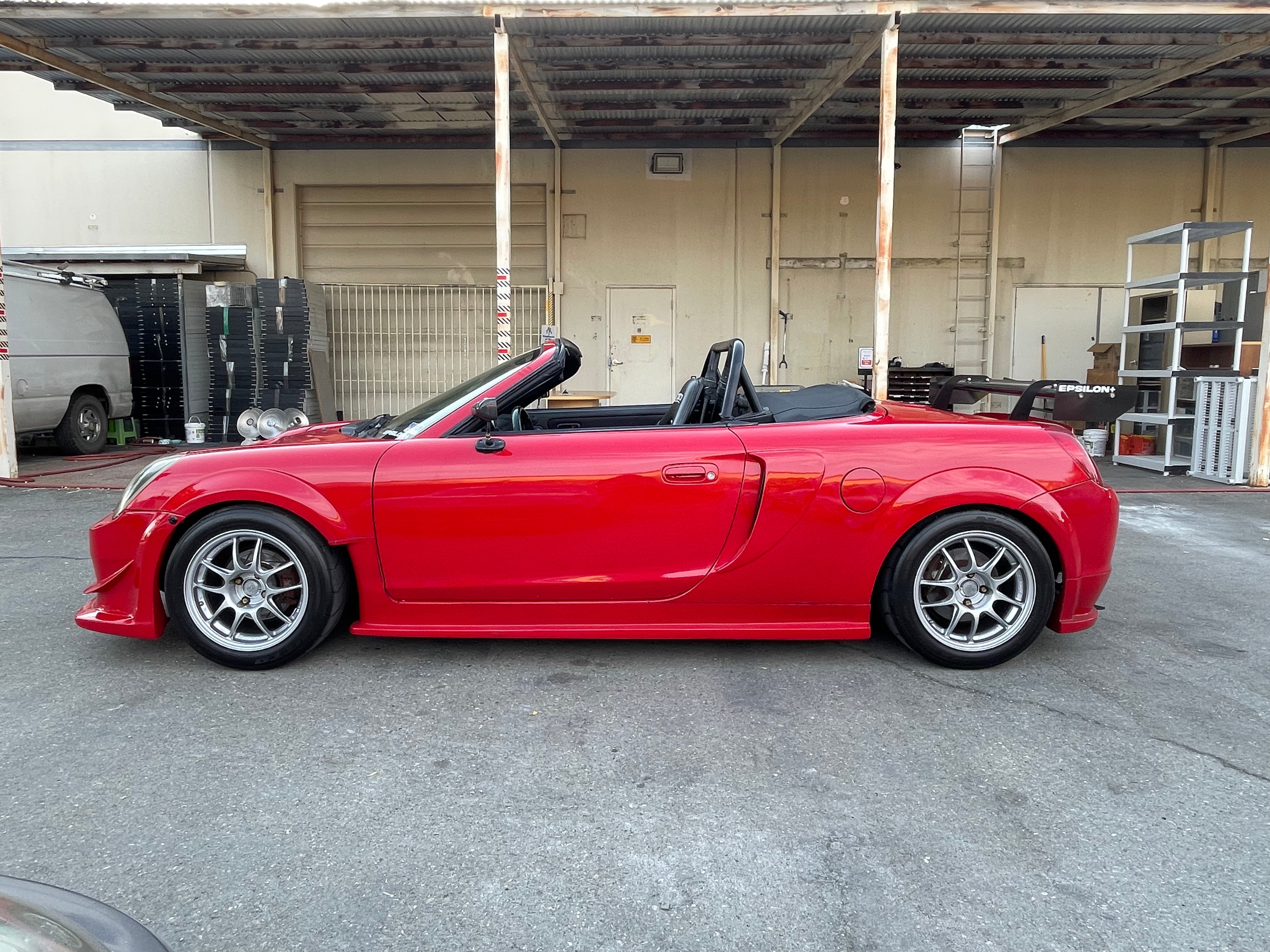 Side profile of a red Toyota MR2 Spyder with the side skirt and fender combo installed