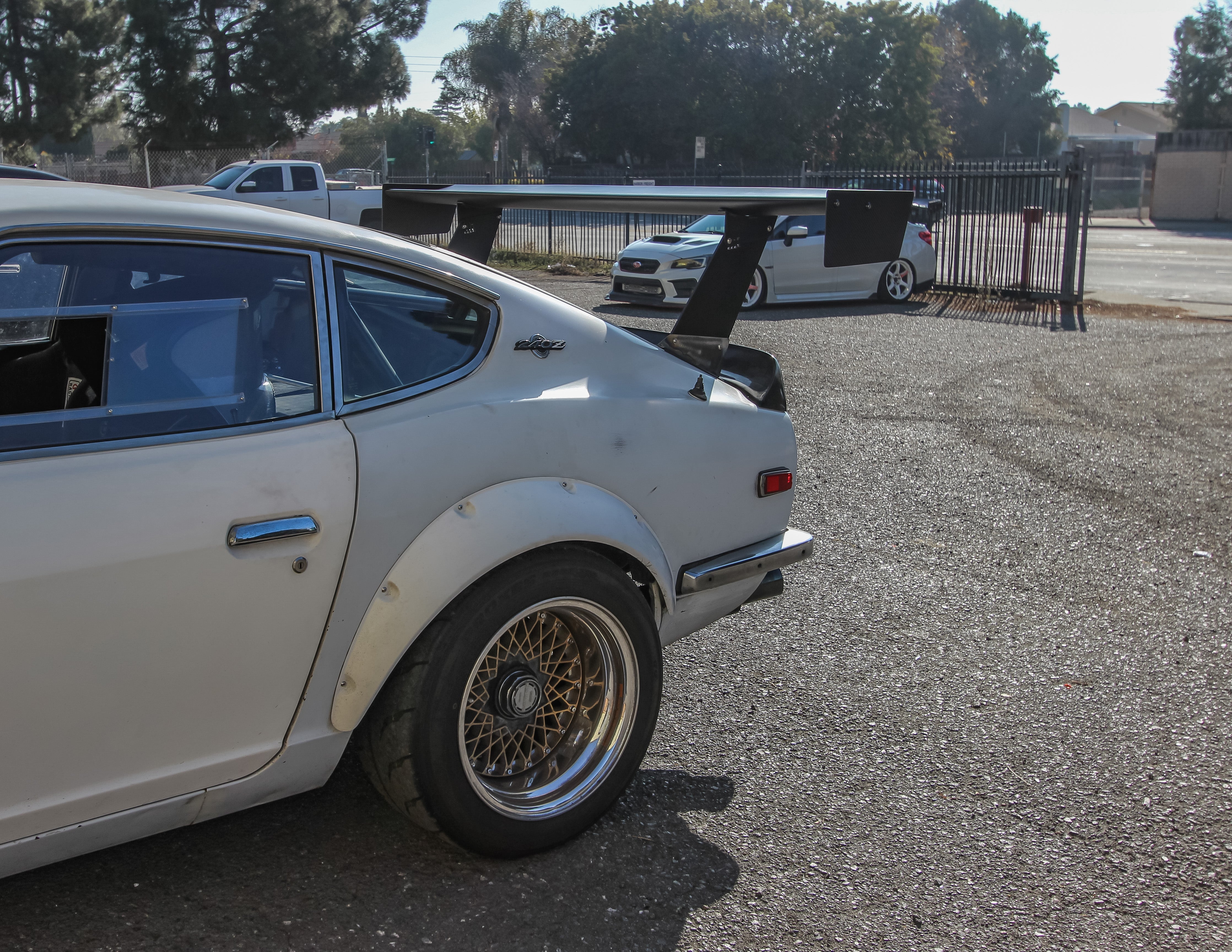 Rear three-quarter view of a silver Datsun 240Z with GT wing and bronze wheels