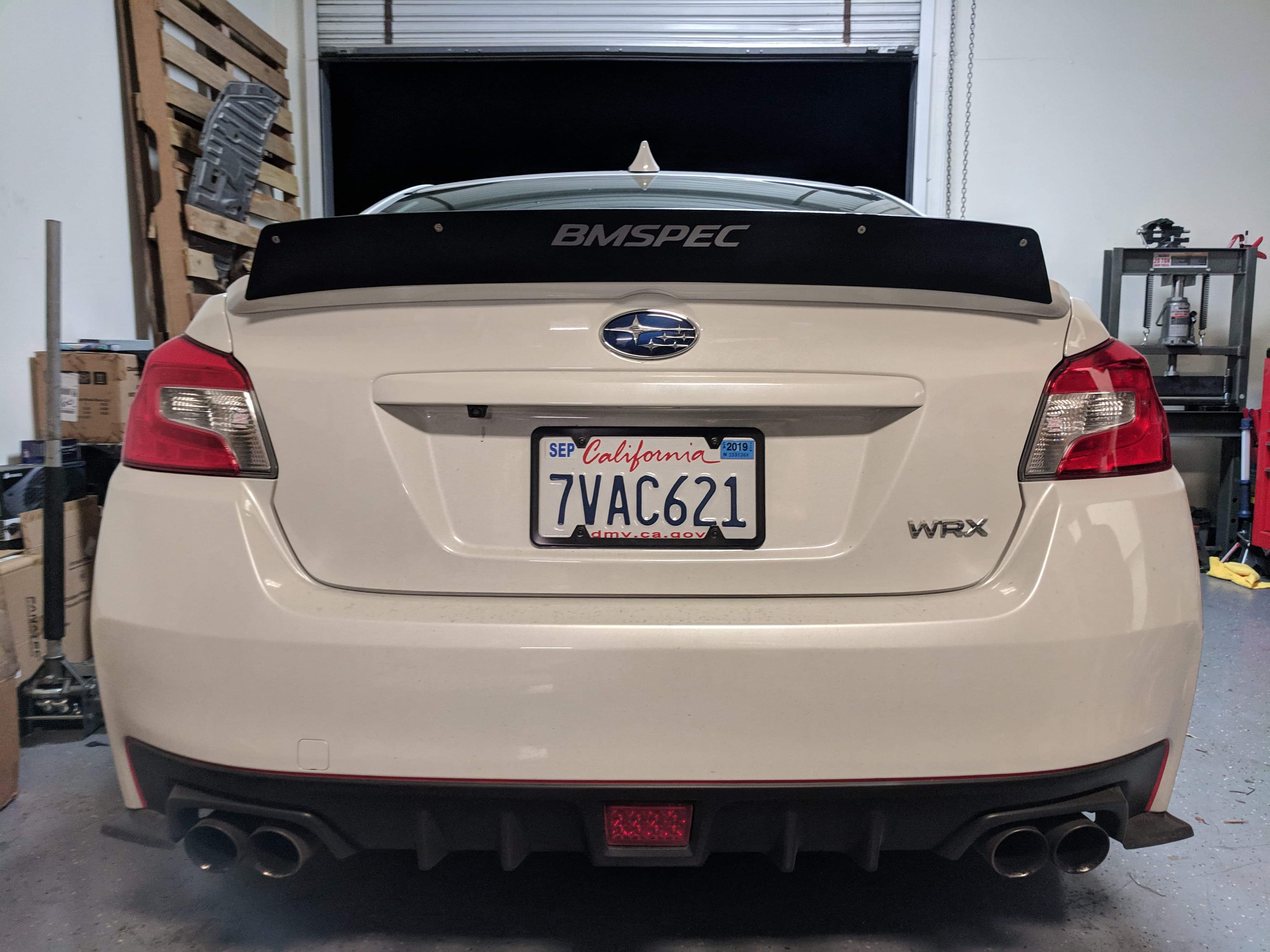 Rear view of a white Subaru WRX VA with spoiler extension in a garage