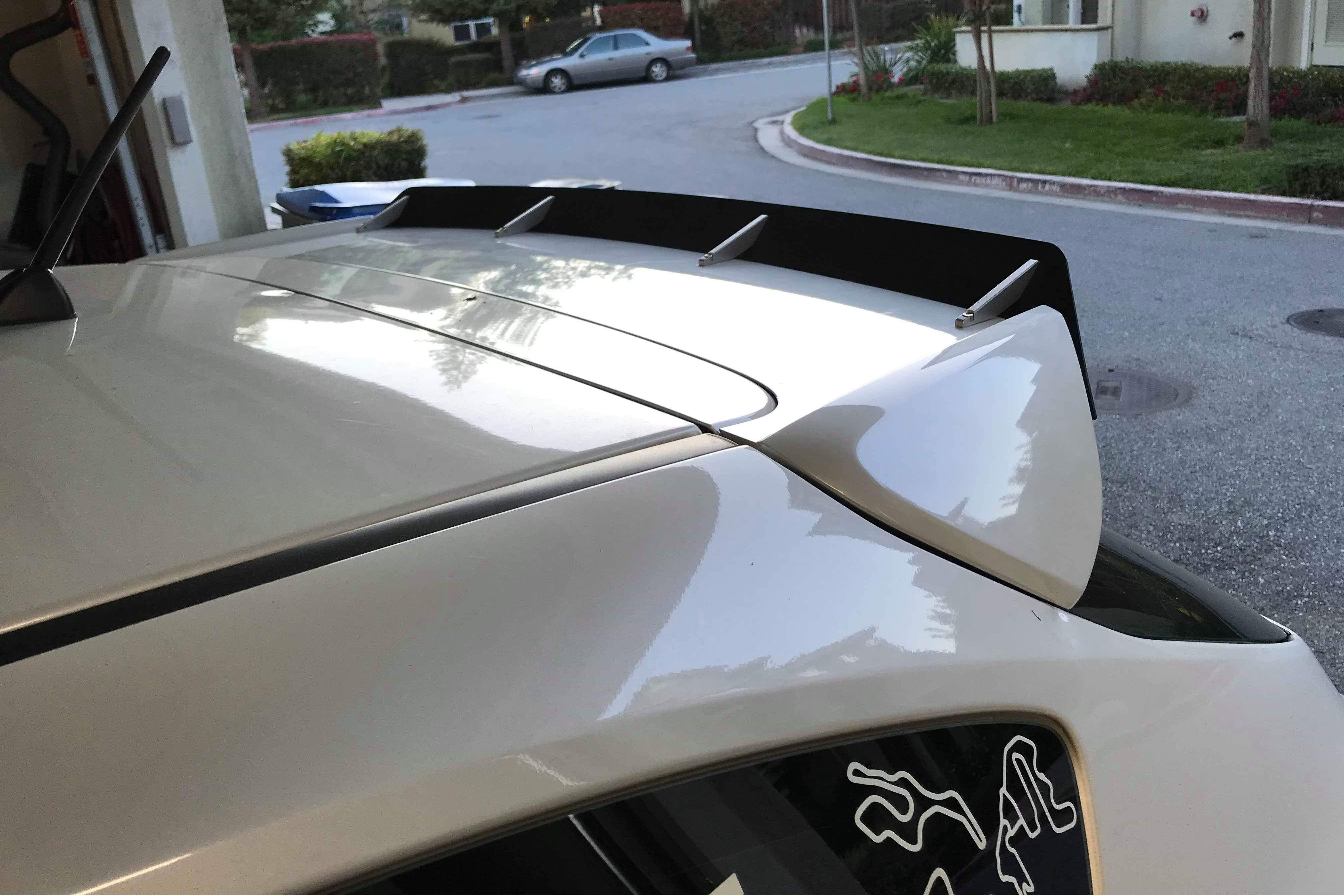 Close-up of the spoiler extension on a white Subaru STI Hatchback in a driveway