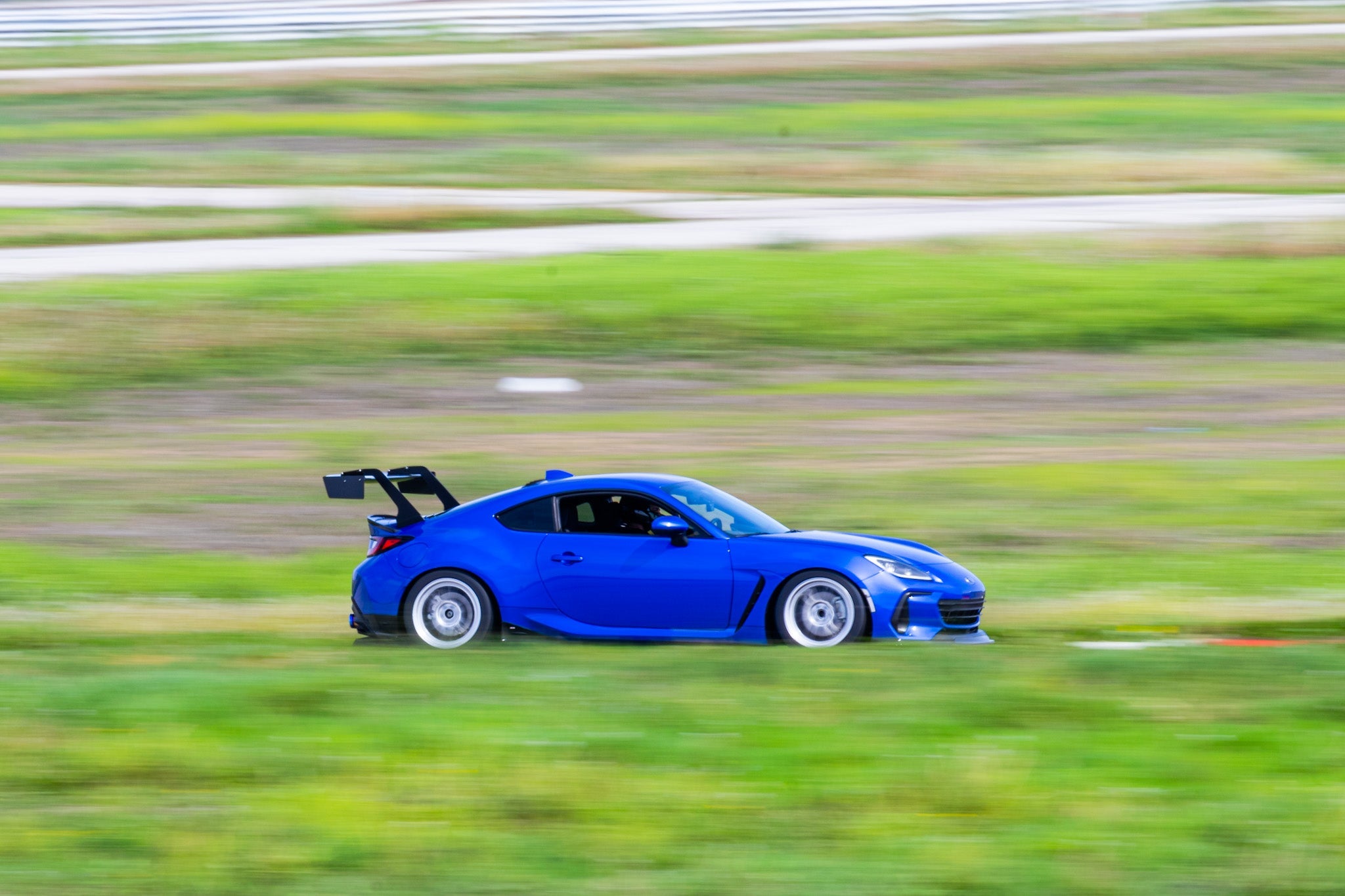 Blue Subaru BRZ ZN8 motorsport car with GT wing panning shot on a track