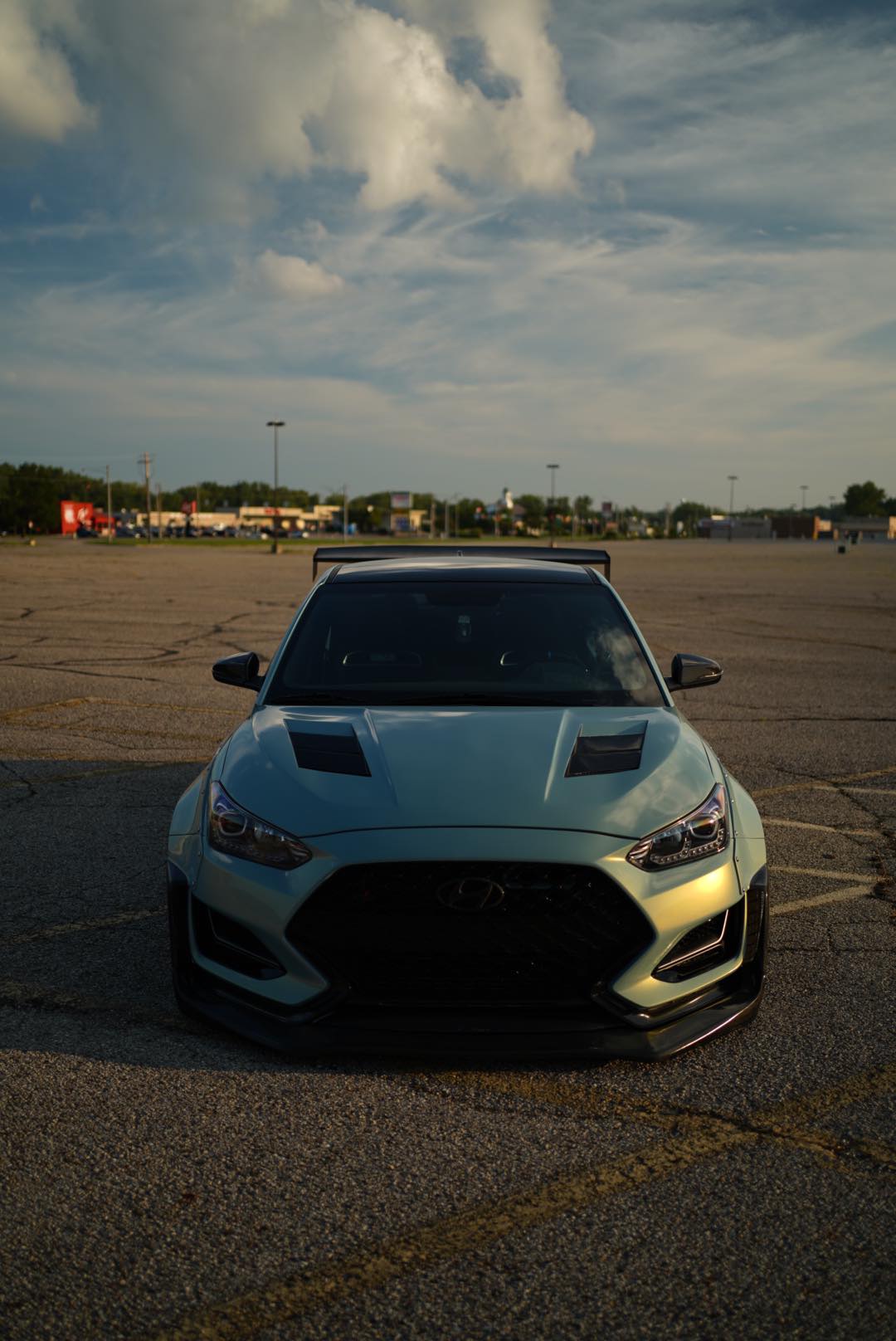 Front three-quarter low-angle view of a teal Hyundai Veloster JS with GT wing