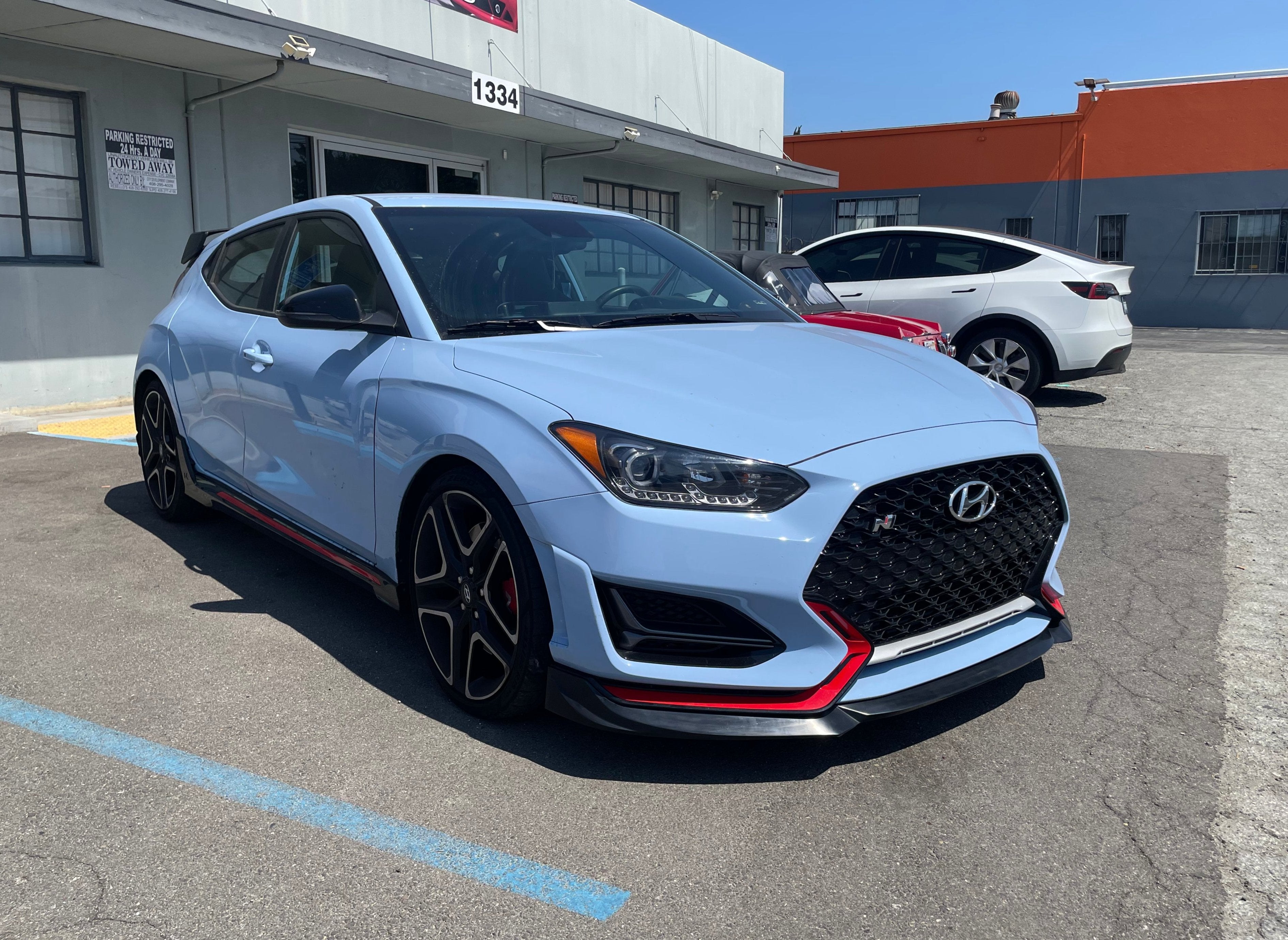 Front three-quarter view of a light blue Hyundai Veloster N with the front lip