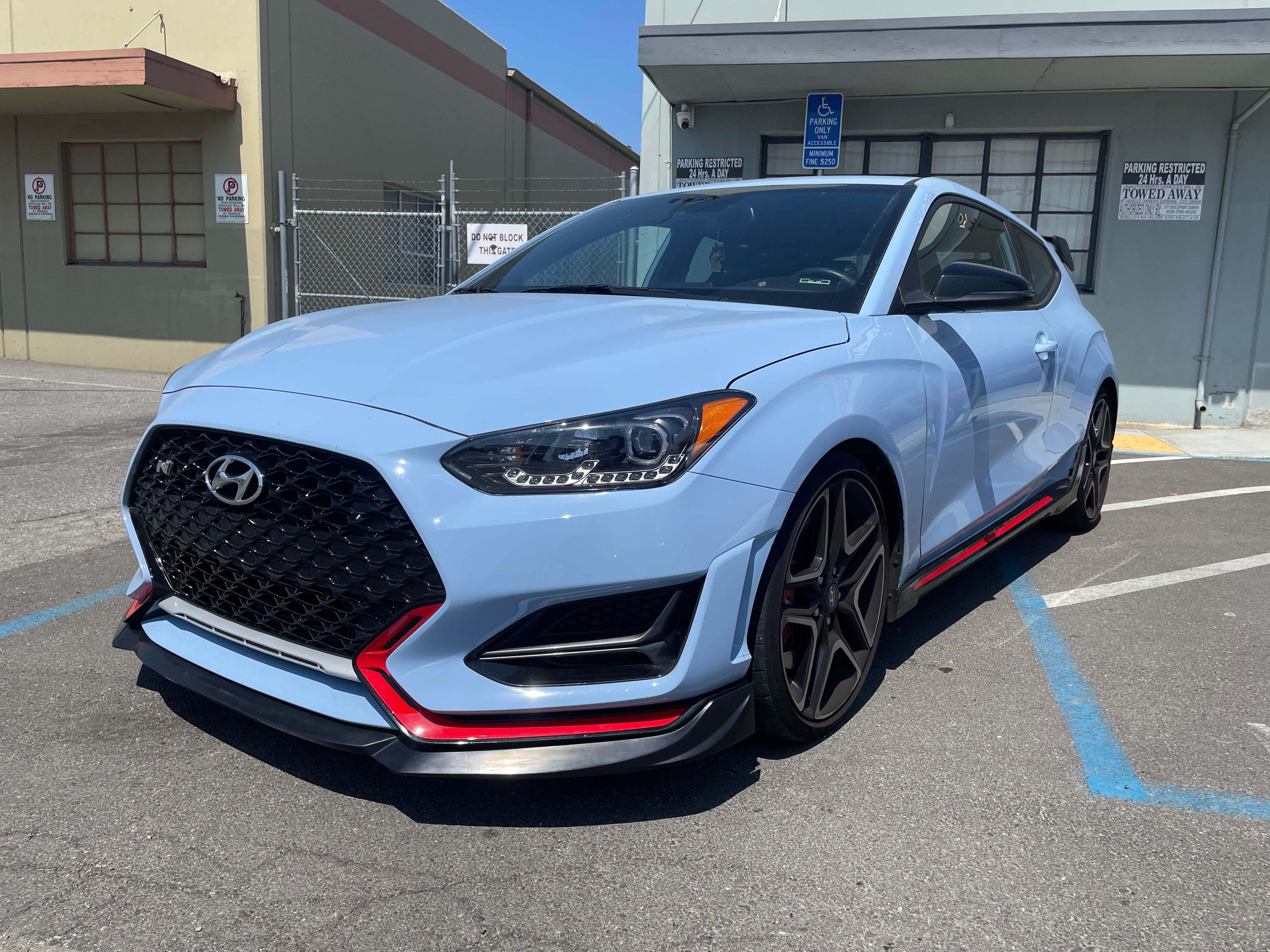 Front three-quarter view of a Hyundai Veloster N with front lip and red trim
