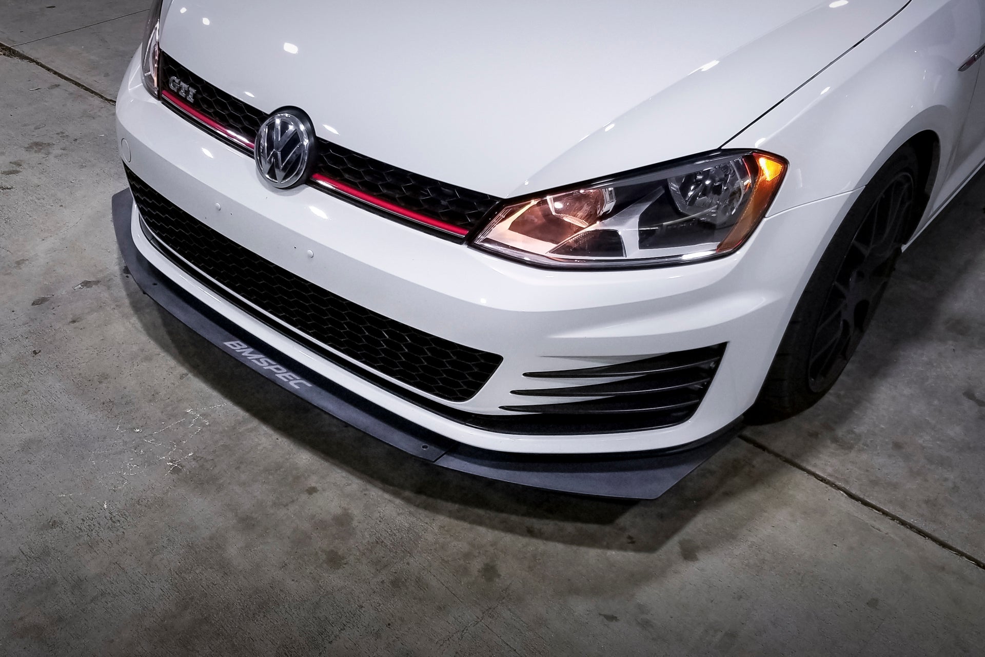 Close-up front view of the Epsilon+ front lip on a white Golf GTI at night