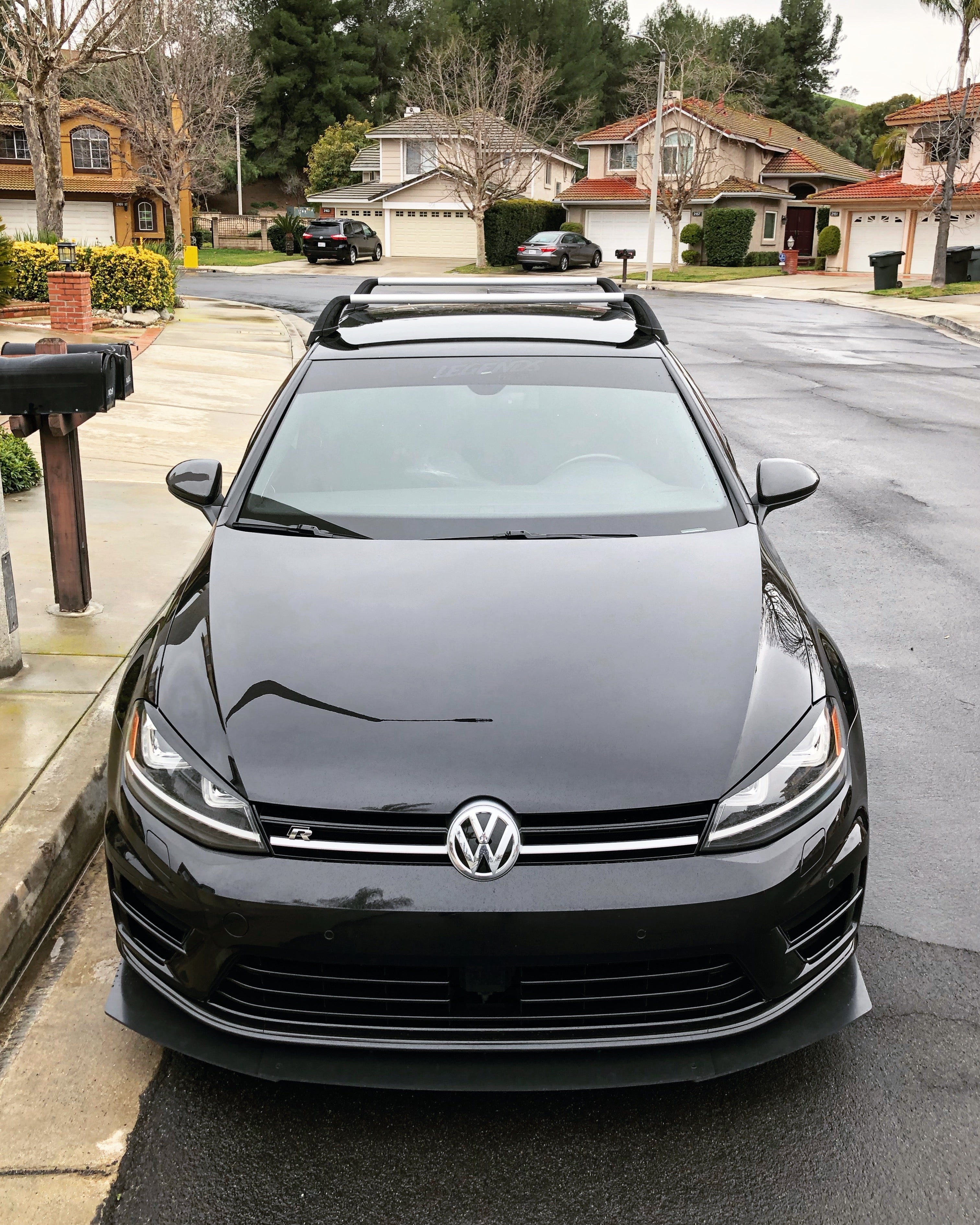 Front-on view of a black Volkswagen Golf R with Epsilon+ front lip in a driveway