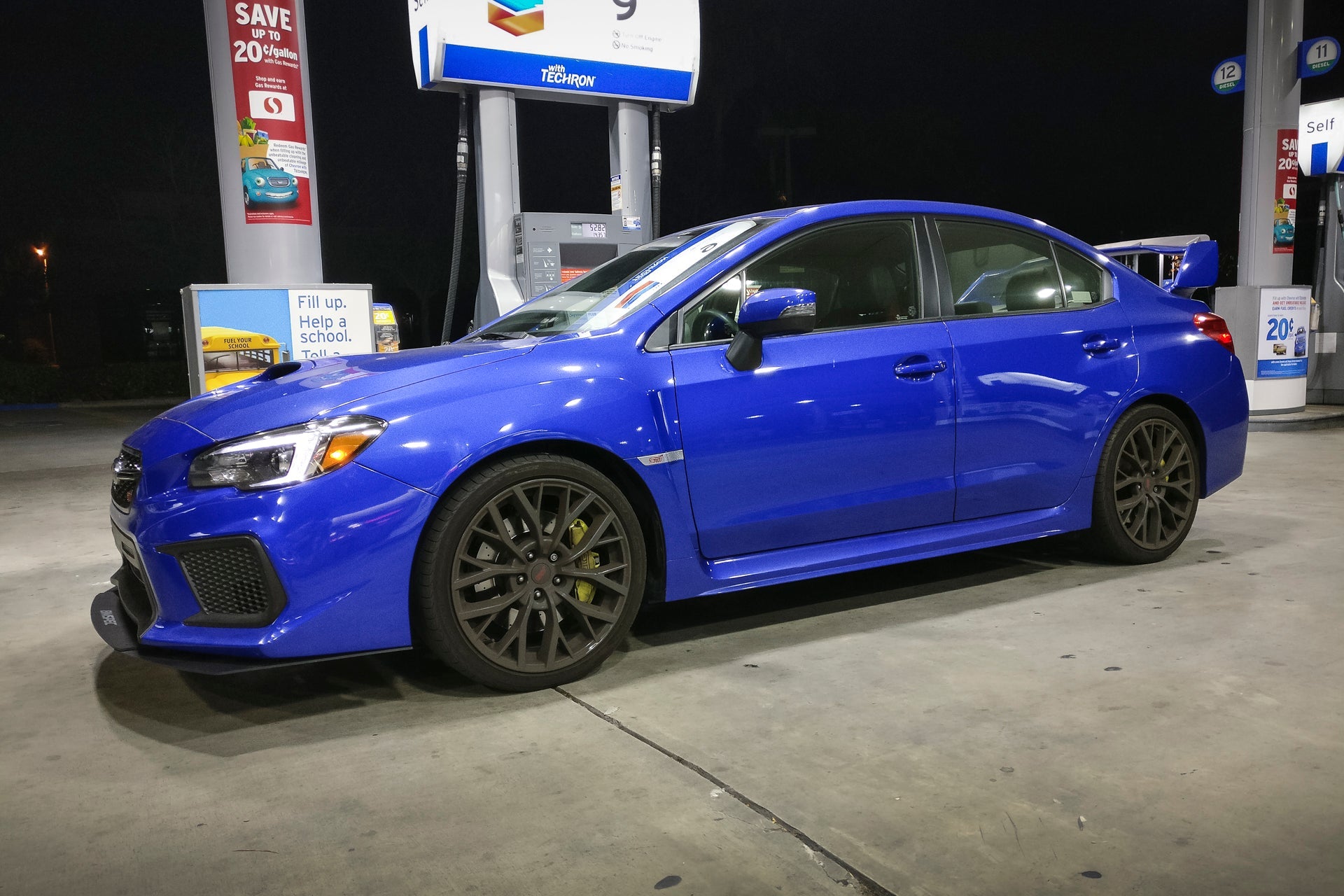 Side profile of a blue Subaru WRX STI with front lip at night