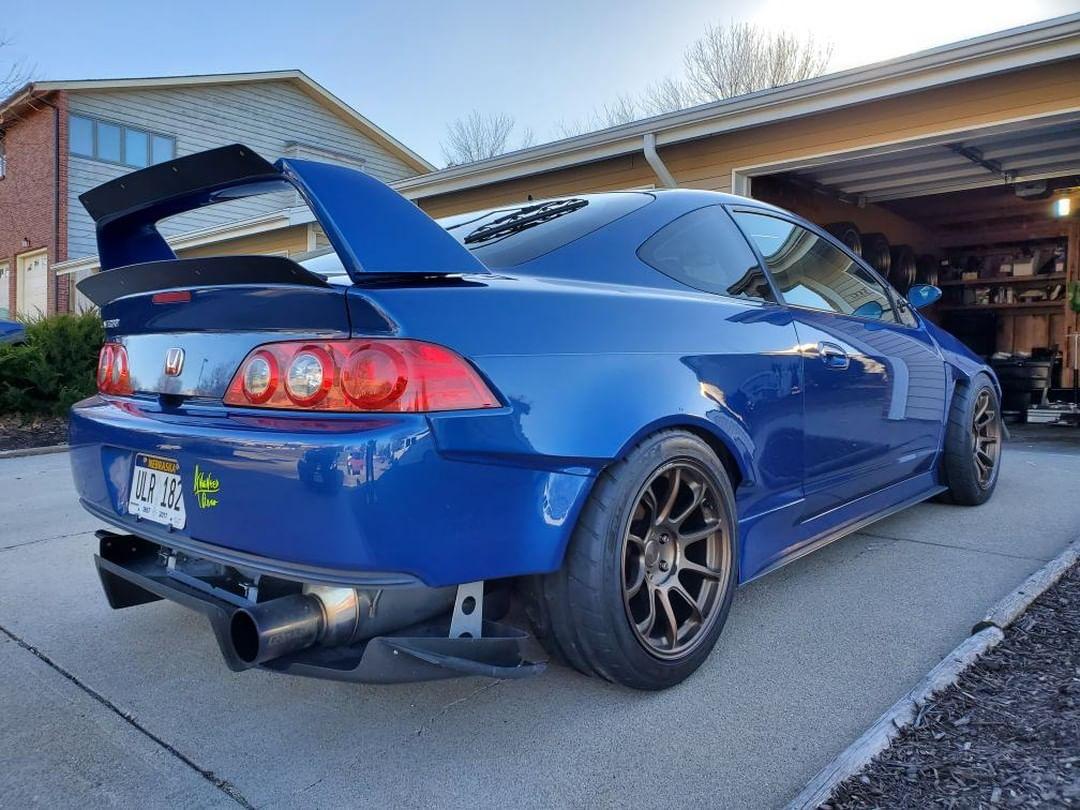Rear three-quarter view of a blue Acura RSX DC5 with the lower spoiler extension