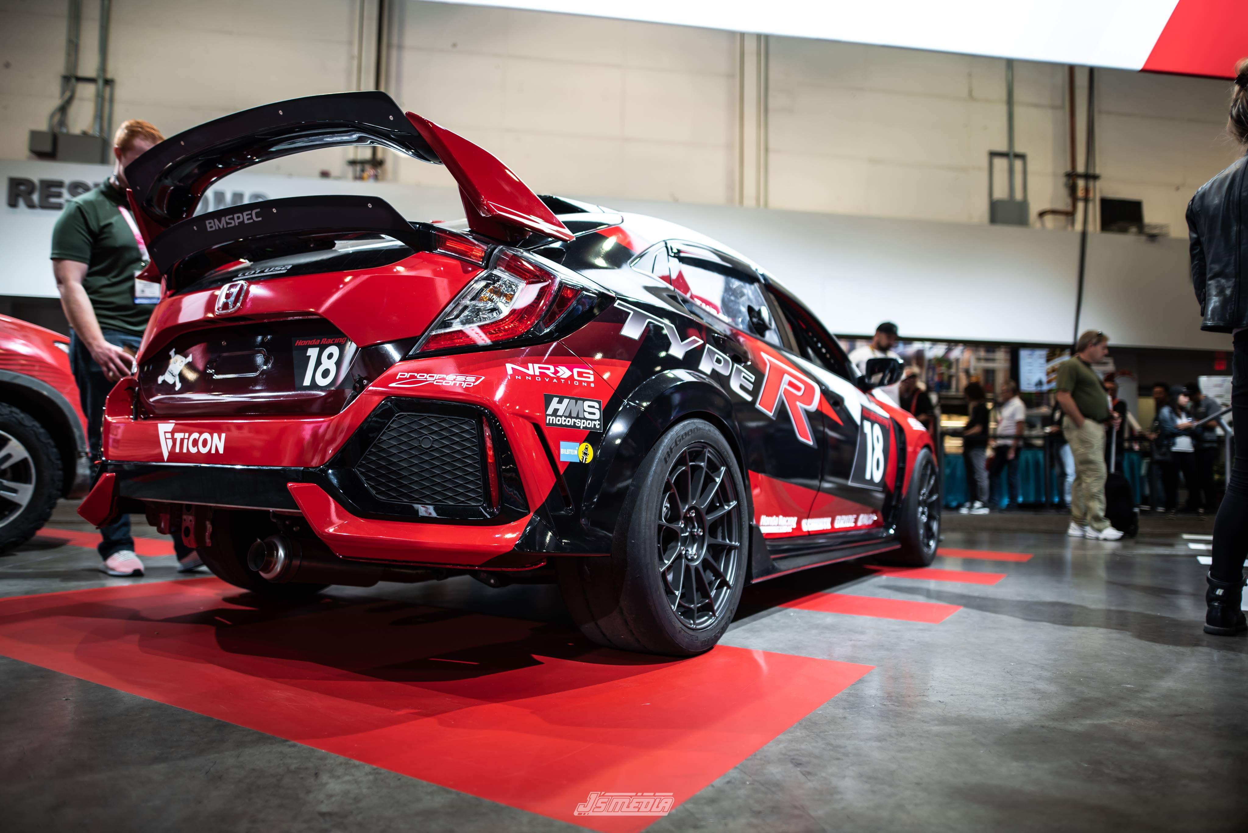 Red Civic Type R race car with upper spoiler extension at an indoor expo
