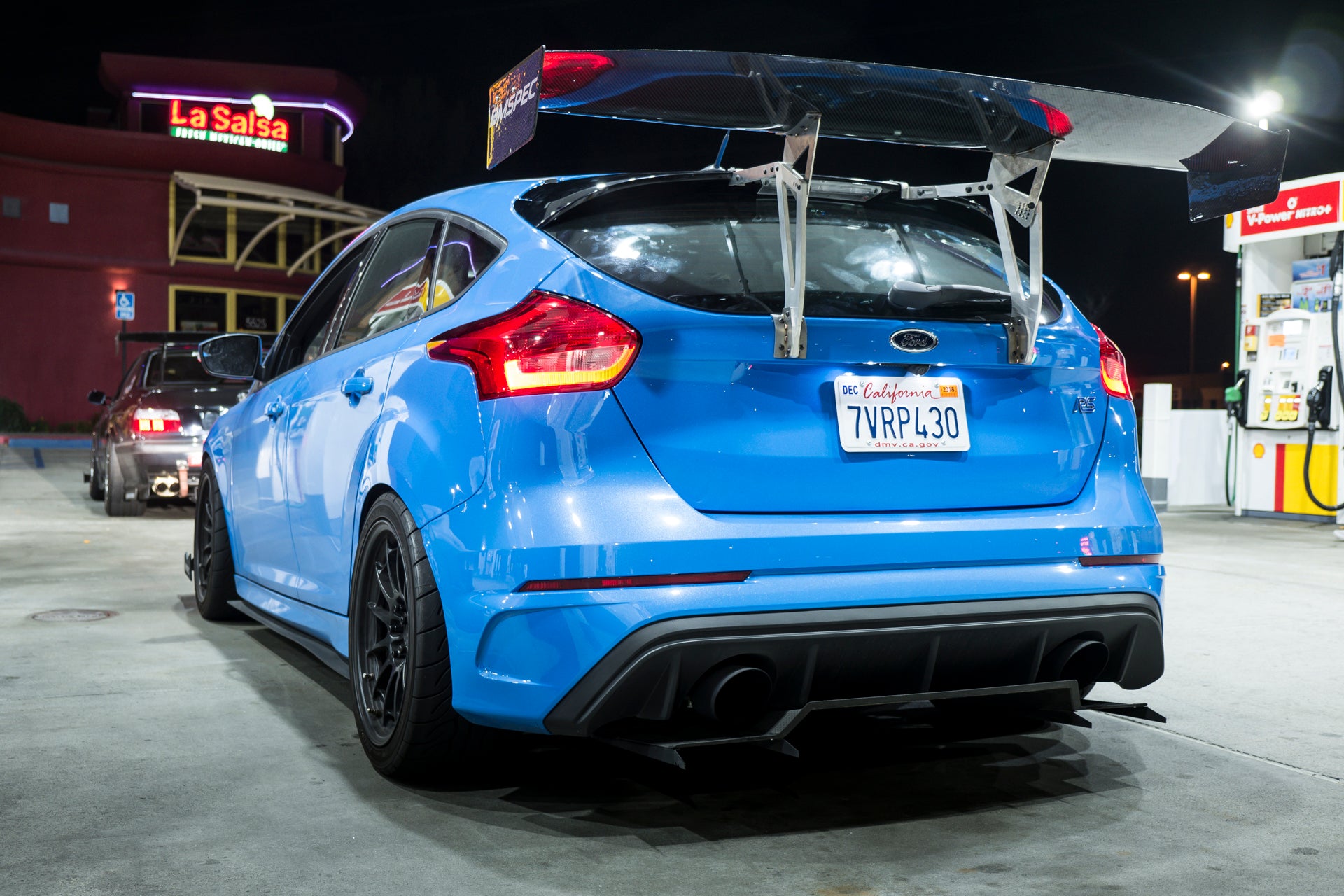 Blue Ford Focus RS with V1+ diffuser and GT wing parked at a gas station at night