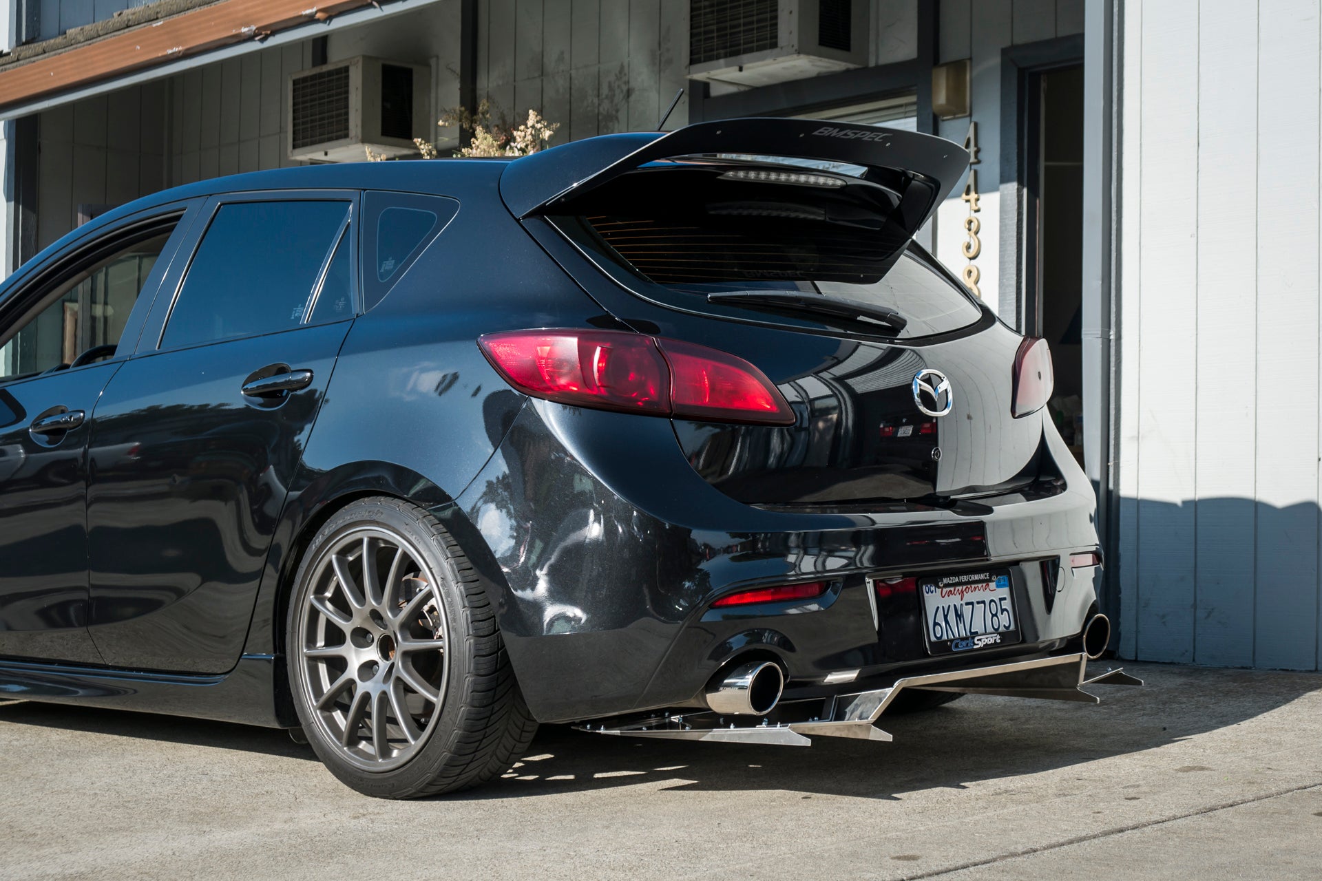 Rear three-quarter view of a black Mazdaspeed3 Gen2 showing the V1+ diffuser under the bumper